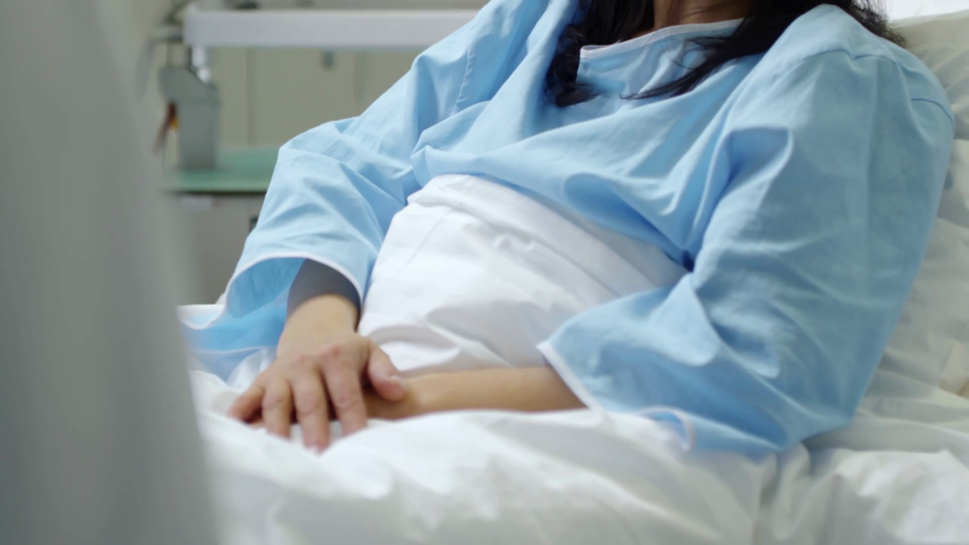 videoblocks-tilt-up-of-cheerful-female-patient-in-hospital-gown-chatting-and-shaking-hands-with-unrecognizable-doctor_sfzuaiwsdf_thumbnail-full01